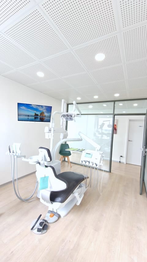 Sala de tratamiento con sillón dental KaVo, techo acústico y mampara de cristal