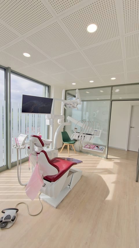 Sala de tratamiento luminosa con sillón dental y gran ventanal