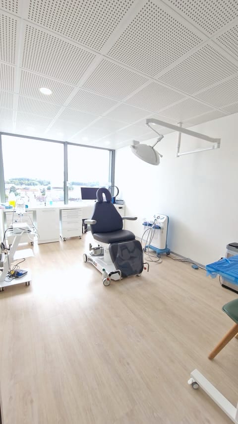 Sala de cirugía con sillón de paciente, lámpara quirúrgica y vistas a la ciudad